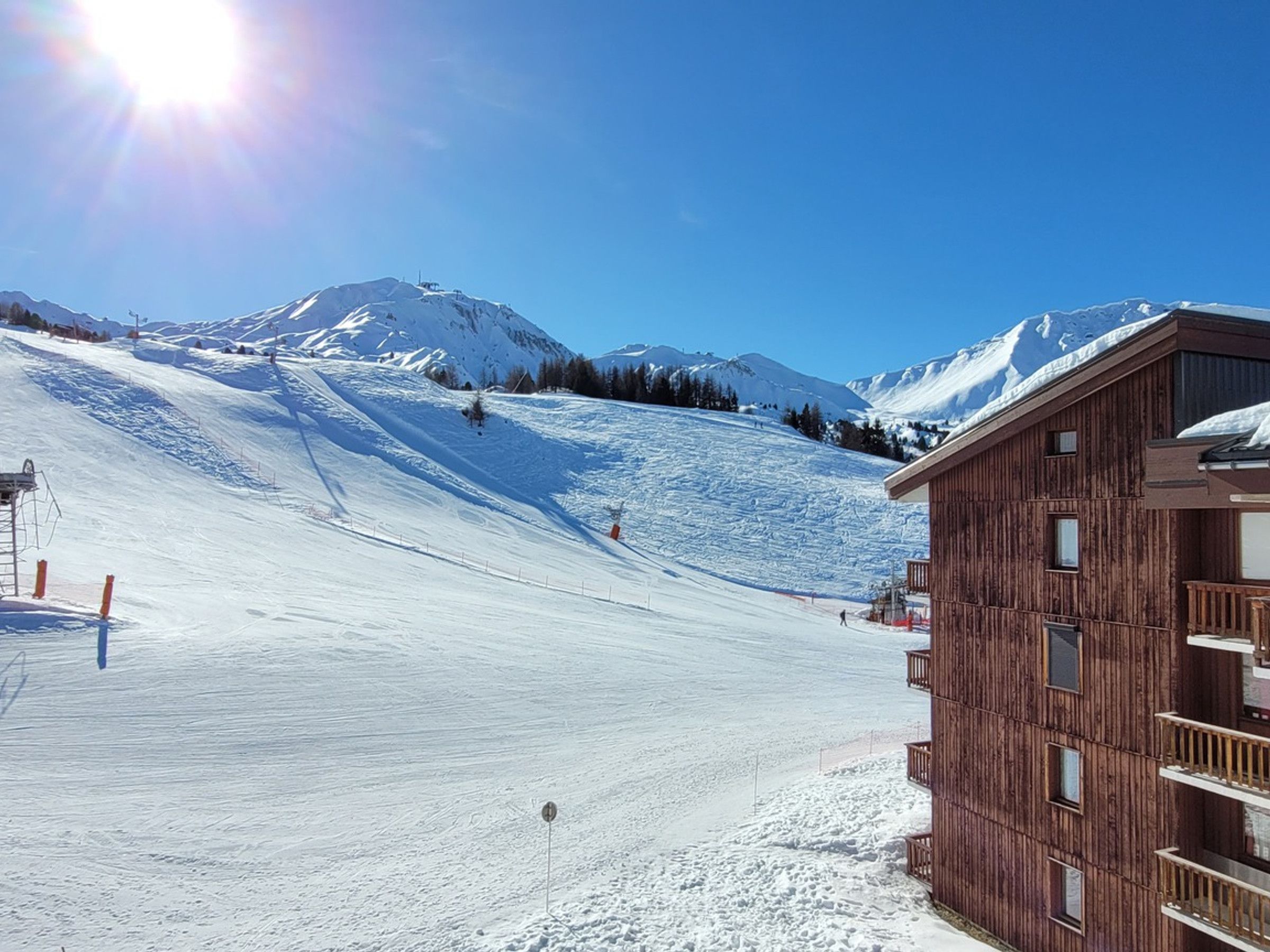 Een piste bedekt met sneeuw, met een houten gebouw aan de rechterkant.