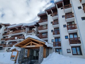 A multi-story hotel with balconies and a wooden entrance labeled "LES HAMEAUX 1".