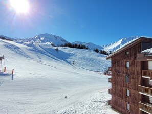 Pista de esqui coberta de neve com um edifício de madeira à direita.