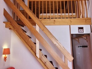 Uma escada de madeira com um quarto no mezanino.
