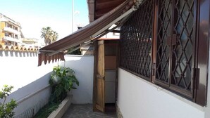 A narrow stone-paved corridor with a wooden door and a metal gate. - Cottage 30 steps from the sea (Fiumicino)