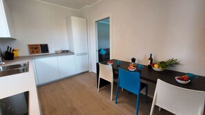 A modern kitchen with white cabinets, a black countertop, and a dining area with blue chairs and a dark table. - Villa Silvia, with private heated pool and garden. (Solarolo)