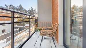 A balcony with wicker chairs, a view of a snowy landscape, and a building in the background. - Apartamenty Sun & Snow Double Rest (Wladyslawowo)