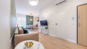 A modern living room with a sofa, a dining area, a TV, and a wooden door. - Apartamenty Sun & Snow Double Rest (Wladyslawowo)