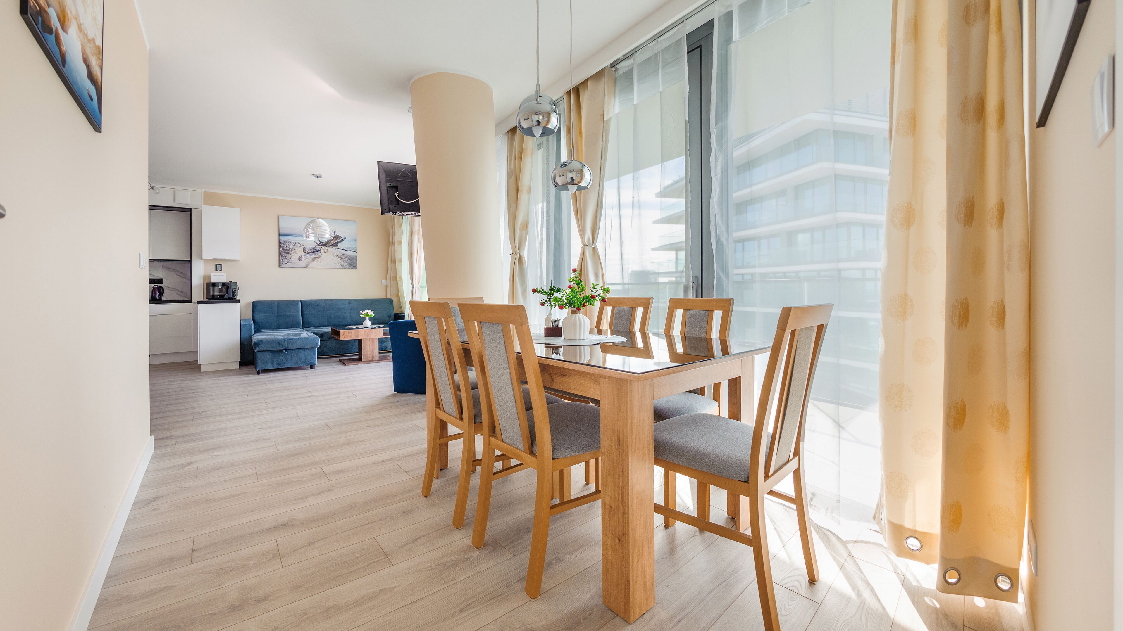 A modern living room with a dining area, wooden furniture, and large windows.