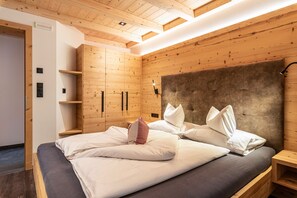 Un dormitorio moderno con cabecera de madera, cama con ropa de cama blanca, una mesita de noche y estanterías empotradas.