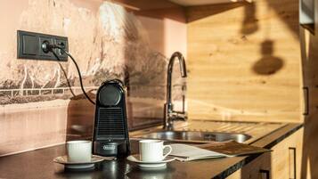 Eine Küchenzeile mit Kaffeemaschine, zwei Tassen, einem Spülbecken und einer Holzrückwand.