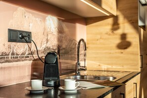 Eine Küchenzeile mit Kaffeemaschine, zwei Tassen, einem Spülbecken und einer Holzrückwand.