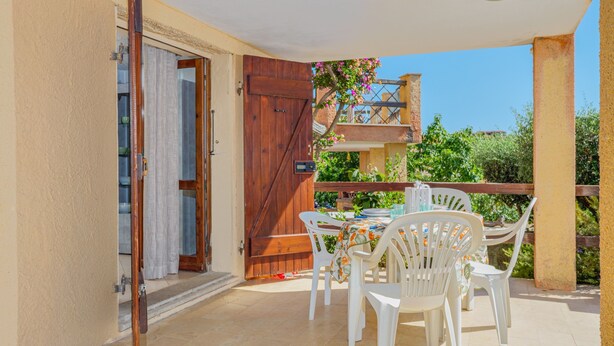 Une terrasse extérieure avec une table et des chaises, une porte en bois et une vue sur la verdure.