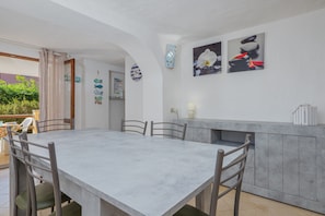 A dining area with a large table and chairs, a kitchen counter, and decorative wall art.