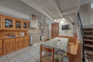 A kitchen with wooden cabinets, a dining table with a floral tablecloth, and a staircase.