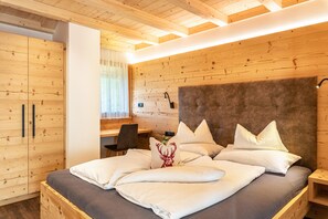 A wooden-paneled room with a bed, a desk, and a chair.
