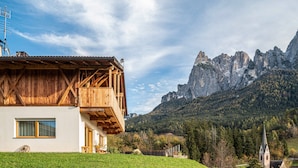 A wooden chalet with a balcony, a window, and a view of a mountain. - Holiday Apartment "Zu Grof Morgenrot" (Castelrotto)