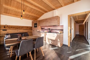 A modern kitchen with wooden cabinetry, a dining area with a wooden table and chairs, and a hallway with wooden flooring.