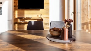 A wooden dining table with a bowl of nuts and two vases on a placemat. - Holiday Apartment "Zu Grof Morgenrot" (Castelrotto)