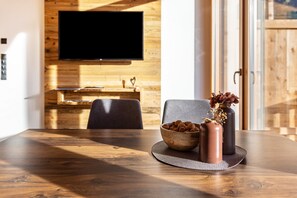 A wooden dining table with a bowl of nuts and two vases on a placemat. - Holiday Apartment "Zu Grof Morgenrot" (Castelrotto)