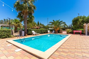 A rectangular swimming pool with a tiled deck, surrounded by palm trees and a sign that reads 'Sanbiter.' - Holiday Home 'Villa Relax Due' with Shared Pool & Wi-Fi (Galatone)