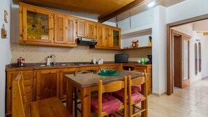 A kitchen with wooden cabinets, a tiled backsplash, a dining table with chairs, and a black television. - Holiday Home 'Villa Relax Due' with Shared Pool & Wi-Fi (Galatone)