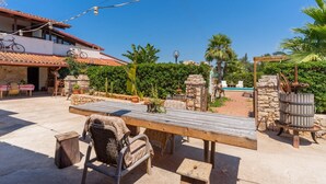 An outdoor patio with a wooden table and wicker chairs, surrounded by stone walls and potted plants. - Holiday Home 'Villa Relax Due' with Shared Pool & Wi-Fi (Galatone)