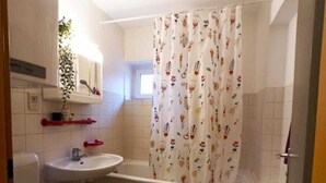 A bathroom with a toilet, sink, and bathtub. - Cozy fresh apartment with rustic roof in quiet area (Graz)