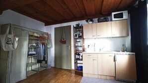 A compact kitchen with wooden cabinets, a microwave, and a sink. - Cozy fresh apartment with rustic roof in quiet area (Graz)