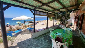 A covered outdoor seating area with a view of the beach and sea. - Strandhaus 'Perla di Mare' direkt am Meer (Capoliveri)