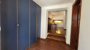 A hallway with blue doors, a kitchen area with white cabinets, and a tiled floor. - Strandhaus 'Perla di Mare' direkt am Meer (Capoliveri)
