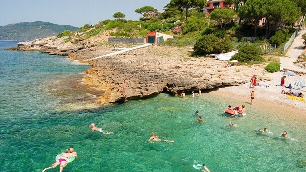 A coastal beach with clear water, rocky terrain, and buildings in the background. - Strandhaus 'Perla di Mare' direkt am Meer (Capoliveri)