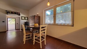A dining area with a table, chairs, and a window with lace curtains. - Strandhaus 'Perla di Mare' direkt am Meer (Capoliveri)
