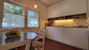 A kitchen with white cabinets, a dining table with chairs, and a fruit bowl.