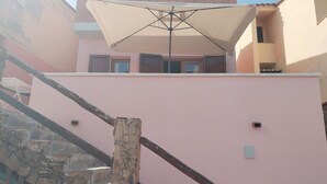 Un edificio rosa con una escalera de piedra y un paraguas grande.