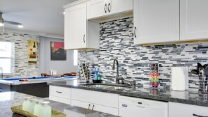 Une cuisine moderne avec des meubles blancs, un pare-feu en carrelage et un plan de travail en granit.