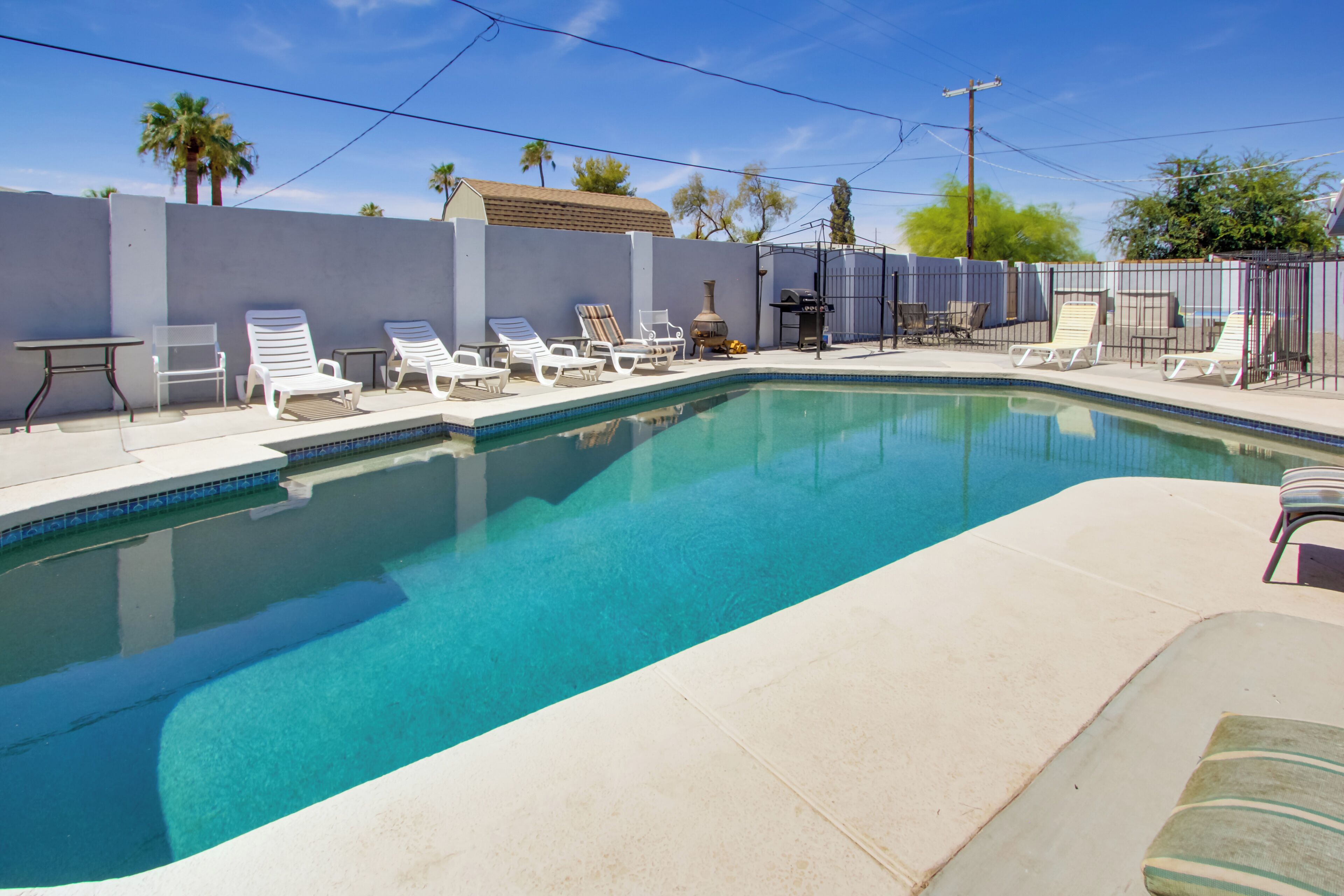 Une piscine avec des chaises longues et un espace patio.