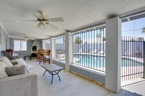 Amplia sala de estar con vista a la piscina, ventiladores de techo y chimenea.