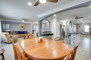 Amplia sala de estar con una mesa de comedor de madera, asientos cómodos y una cocina con electrodomésticos modernos.