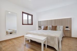 Ein Schlafzimmer mit Bett, Nachttisch, Spiegel und Fenster.