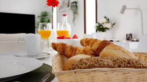 A breakfast setting with croissants, bread, and orange juice on a table. - Holiday Apartment "Crepusculo" with Mountain View, Terrace & Wi-Fi (Puerto del Rosario)