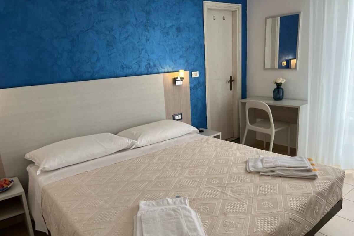 A hotel room with a bed, a desk, and a chair.