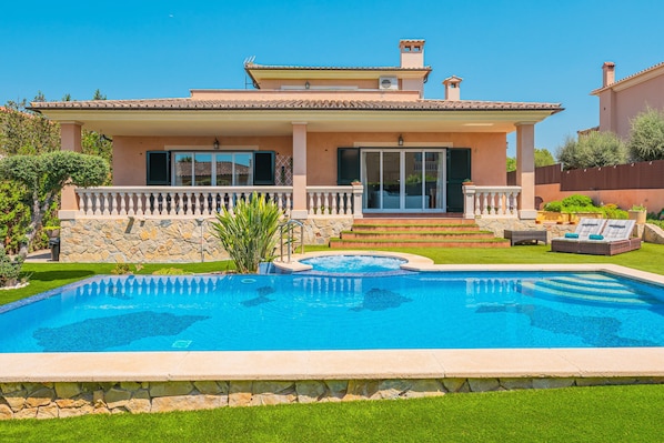 Une maison avec une piscine, un patio couvert et un mur en pierre.