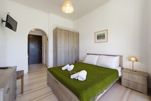 Habitación de hotel con cama, escritorio, televisión, armario y un cuadro en la pared.