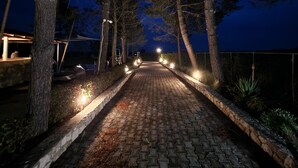 A paved pathway flanked by trees and lit by street lamps, leading towards a distant building. - Studio Apartment 'Alexandra Studio 11' with Private Balcony and Wi-Fi (Lefkimmi)