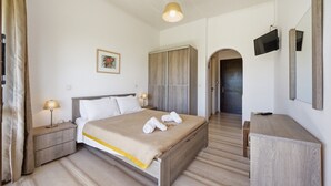 Une chambre d’hôtel comprenant un lit, des tables de chevet, une télévision, une armoire et un miroir.