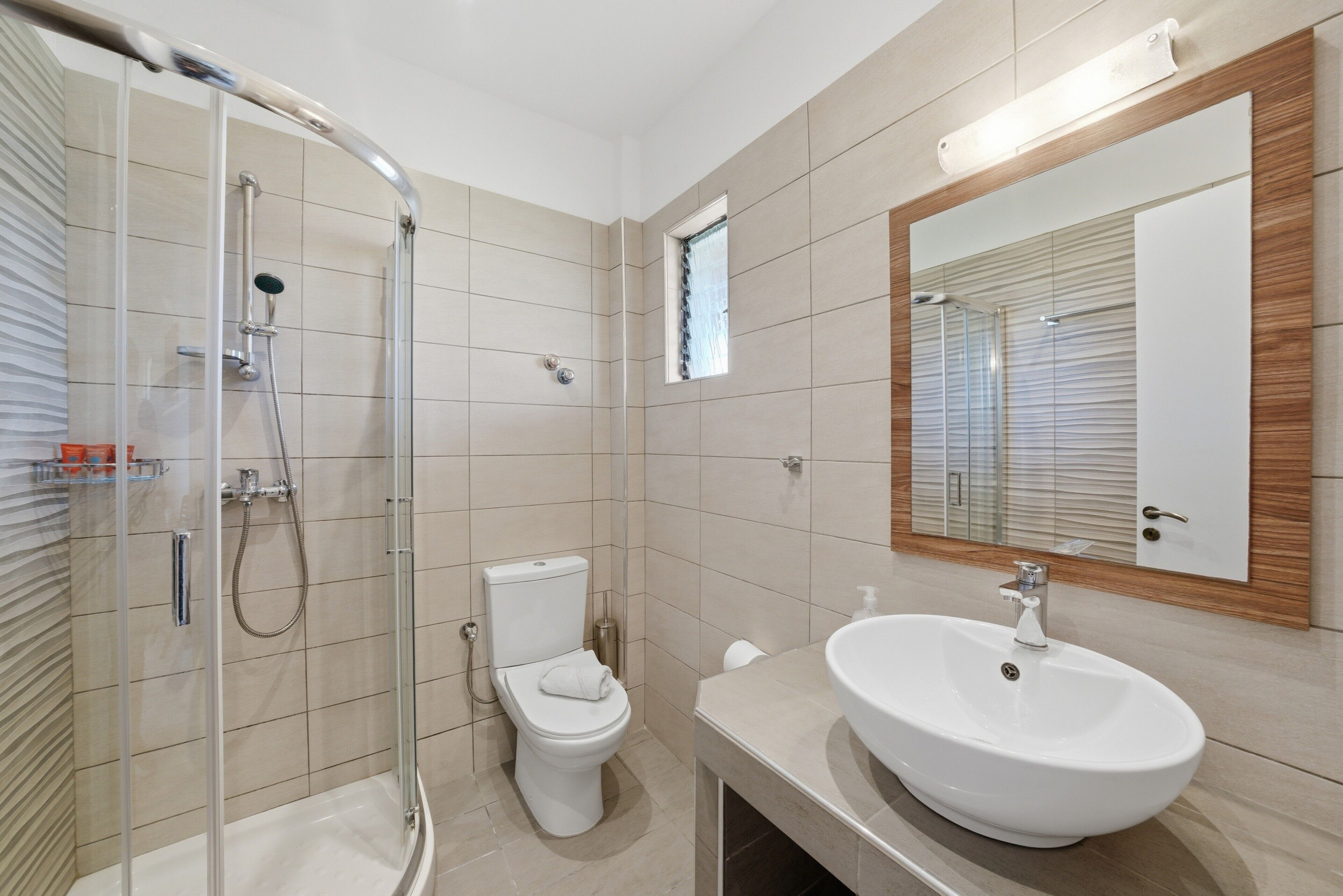 Un bagno moderno con cabina doccia in vetro, un water, un lavandino e uno specchio.