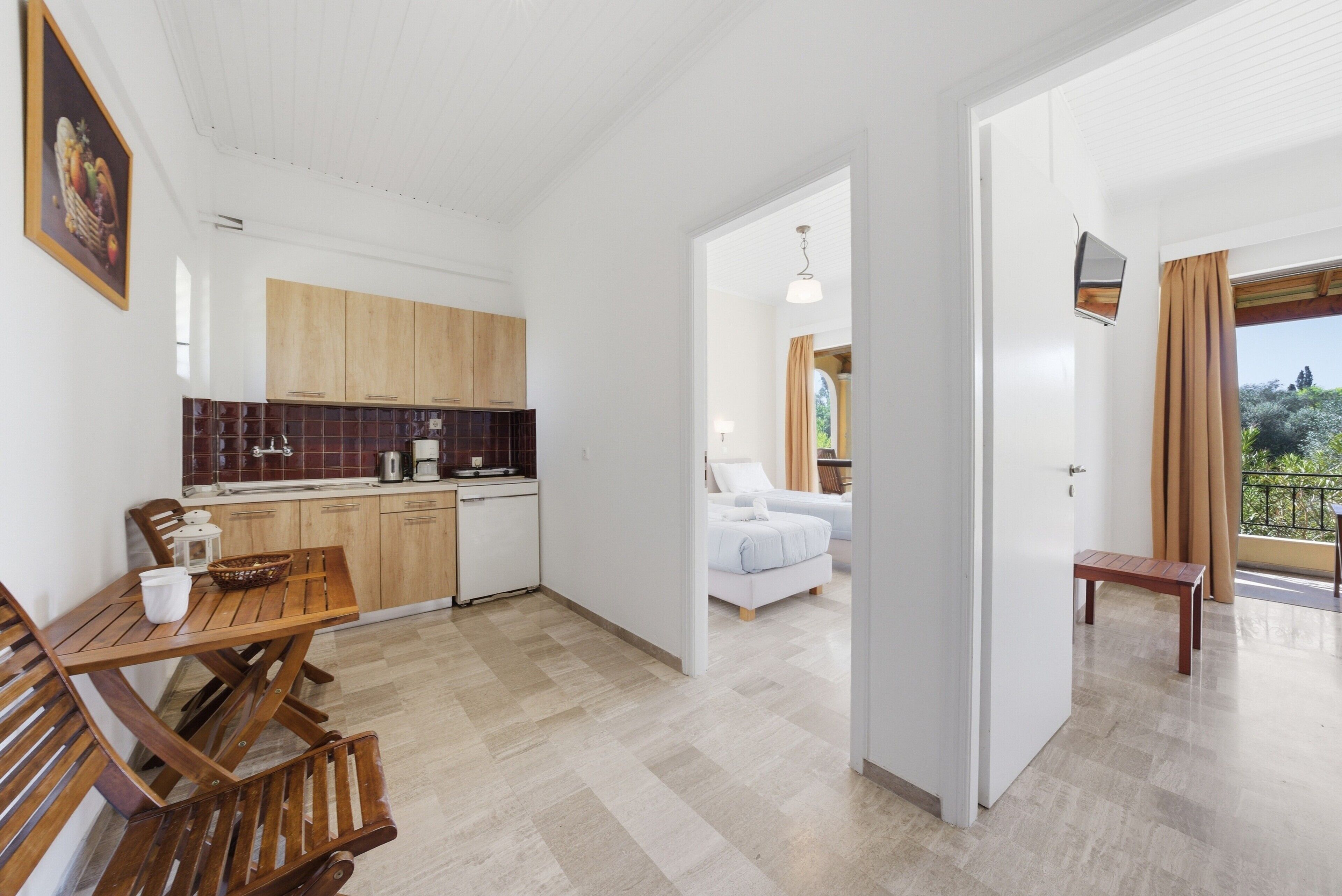 Una cucina moderna con mobili in legno, un tavolo da pranzo e sedie. Si trova anche una camera da letto con un letto e un balcone con vista.