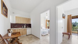Eine moderne Küche mit Holzausstattung, einem Esstisch und Stühlen. Ein Schlafzimmer mit Bett und ein Balkon mit Aussicht.
