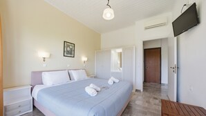 Ein Schlafzimmer mit Bett, Nachttischen, einer Holzbank, einem Fernseher und einem Kleiderschrank.