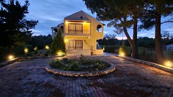 Una casa a due piani con vialetto curvo e giardino paesaggistico.