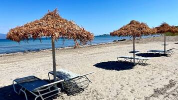 Una spiaggia con lettini e ombrelloni di paglia.