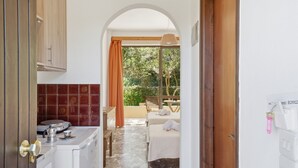 A room with a bed, a washing machine, a small table, and a view of the outdoors. - Studio Apartment 'Alexandra Studio 7' with Private Balcony & Wi-Fi (Lefkimmi)