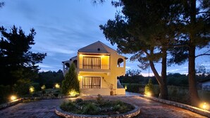 Une maison à deux étages avec une allée circulaire et un jardin aménagé.